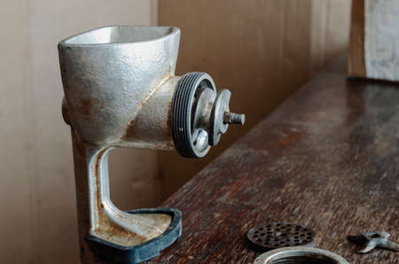 Disassembled manual vintage meat grinder on wooden table. Hand tool for grinding various products. Antique kitchen utensils.の写真素材