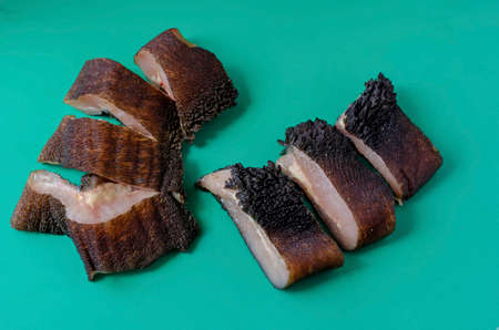 Pieces of raw cow stomach on turquoise. Random pieces Black unpeeled tripe with grass residues. Beef offal. Close-up.の写真素材