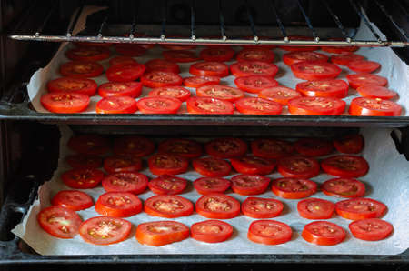 Baking sheet with chopped tomatoes in the oven. Cooking dried ripe vegetables. Dried homemade food.の写真素材