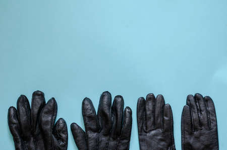 Black leather gloves on light blue background. Pair of male and pair of female gloves. Top view at an angle.の写真素材
