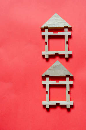 Two Wooden houses from a children's constructor on a coral background. Simple houses from wooden geometric details. Construction and rental of real estate concept. View from above. Copy space.の写真素材