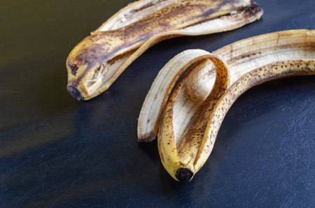 Detailed photo Discarded banana peel on black background. The peel of overripe bananas with brown...