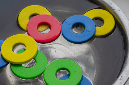 Multi-colored details of children's designer set in metal bowl with water. Cleaning children's toys...