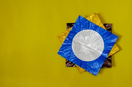 Three square pieces of colored foil on yellow. Pieces of foil brown, blue and yellow with a white...
