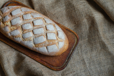 Small business of baking homemade bread background. Lloaf of craft bread on burlap. Top view at an...