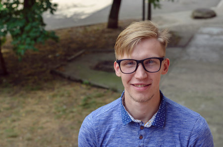 Portrait of a cheerful young man with glasses. A European man looks at the camera. Lifestyle....