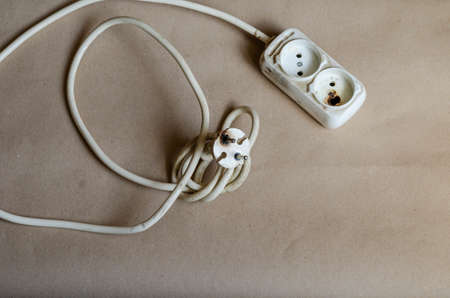 Electrical plug condition, outlet after shock on brown background. White power strip after short circuit. Electrical safety.の写真素材