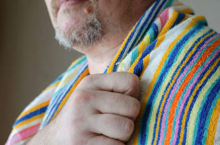 Close-up of a male hand holding a rainbow colored bath towel. A middle-aged Caucasian man with a graying beard and mustache. Selective focus.の写真素材