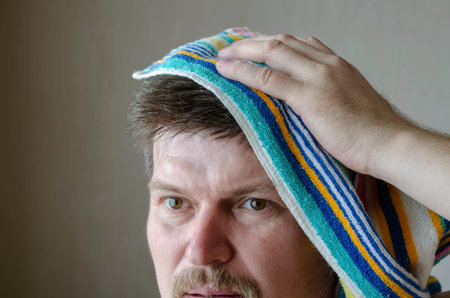A mature man wipes his head with a rainbow-colored bath towel. A middle-aged Caucasian man with a...