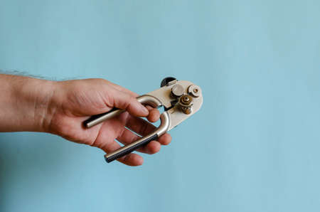 Man's hand holds a can key. Shiny metal special key. Adult Male of European Race Demonstrates Kitchen Accessoriesの写真素材