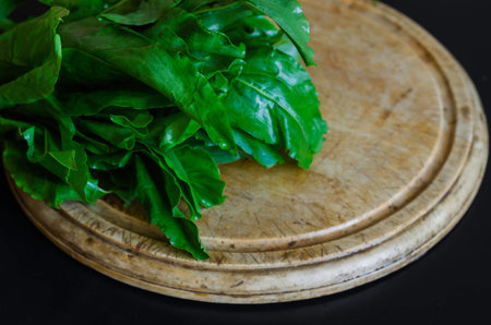 A bunch of raw green sorrel on a wooden chopping board. Washed leaves of sorrel. Cooking. Selective...