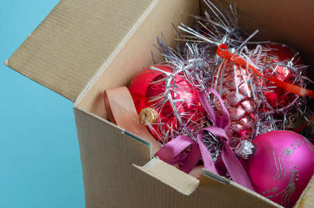 Cardboard box full of Christmas tree decorations. Random glass Christmas tree decorations and tinsel. Celebrating Christmas and New Year. Top view at an angle.の写真素材