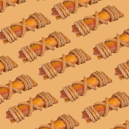 Dried beef tendons for dogs abstract background. Repetitive chewy treats tied with rope. Pet shop, pet supplies.の写真素材