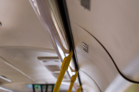 Yellow handrails for passengers inside a public city bus. Fragment of the interior of public...