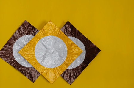 Three square pieces of colored foil on yellow. Pieces of foil brown and yellow with a white circle....