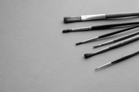 Set of random brushes for painting on light gray textured background. The concept of creativity, art. Copy space. Selective focus. Monochromeの写真素材
