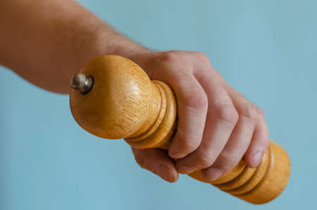 Adult man holds in his hand a wooden pepper mill. Classic spice chopper. Male of European race, 43-45 years old. Kitchen utensilsの写真素材