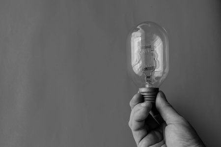 Male hand holds vintage street spotlight incandescent bulb. Tungsten filament glass lamp....