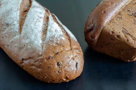 Two random loaves of rye bread on a black background. Demonstration of various varieties of homemade...