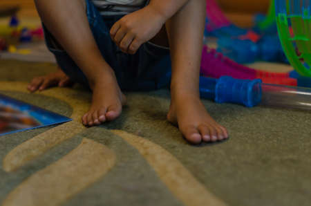 A mixed race boy sits on the floor indoors. Preschool child on the carpet. Happy life. Selective focus.の写真素材