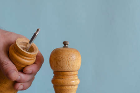 A male hand and two pepper grinders. A man is holding an open Wooden Kitchen Spice Tool. Selective focus.の写真素材