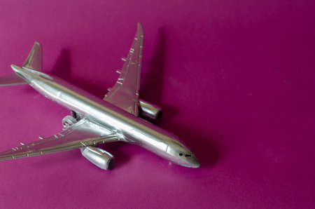 Model of a passenger plane in on a pink background. Silver plane close up. Air transport and tourism. Selective focus.の写真素材