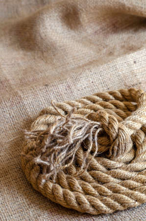 Thick natural rope wound in a reel on sackcloth. Close-up of a laid nautical rope. Marine theme. Selective focus.の写真素材
