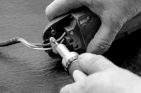 Network splitter and screwdriver in hand. Male hands are repairing an electrical splitter. Electrical safety. Selective focus. Monochromeの写真素材