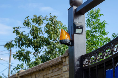 Orange siren with solar motion sensor at the entrance gate to a private residence. The upper part of...
