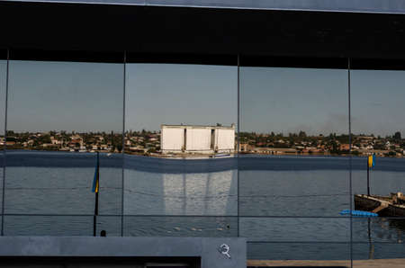 Reflection in the glass facade of a modern building. A modern corporate building by the river. Reflection River and the opposite bank with an elevator. Modern architecture.の写真素材