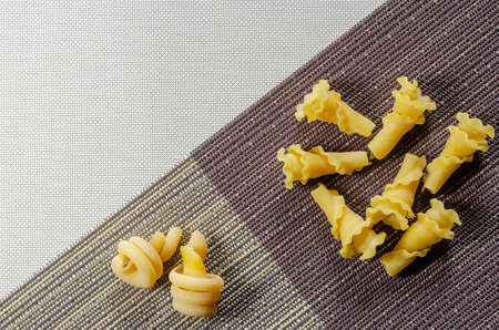 Raw Pasta Gigli and insalatonde on a tricolor background. Varieties of Italian pasta in zonal division. Top view at an angle.の写真素材