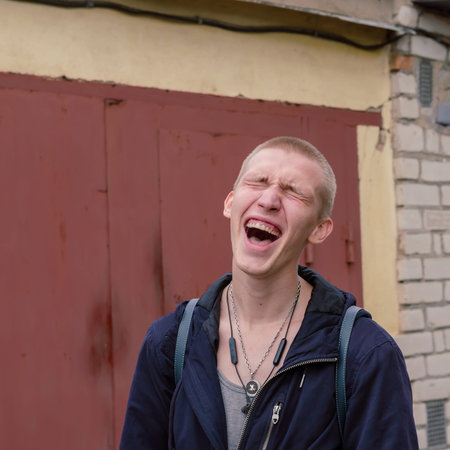Portrait of a young man screaming in pain with closed eyes, hysterical. A man with short hair,...