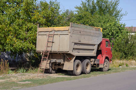 Nikolaev, Ukraine - September 21, 2020: Kamaz dump truck stands on the side of the road. Ladder at the rear of the truck. Truck with high sides and a closed awning body. Cargo transportation services.のeditorial素材