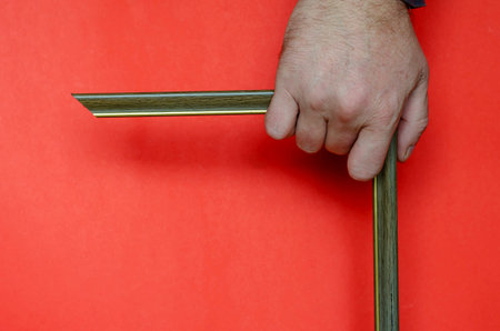 A male hand is holding an empty photo or picture frame on a red background. Bold multitasking...