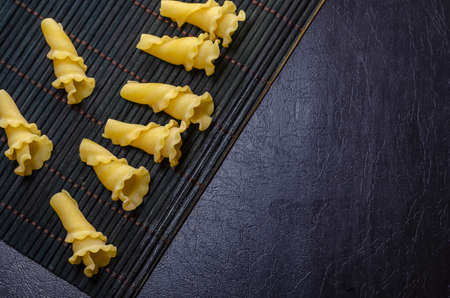 Uncooked Gigli or campanelle pasta On a dark bamboo napkin. Variety of Italian pasta. Mediterranean traditional cuisine.の写真素材