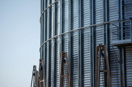 Construction of a metal grain storage. Mechanical jacks around the circumference lift the metal silo...