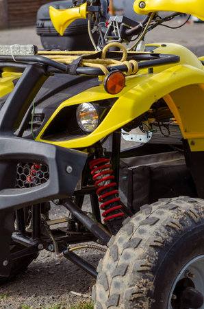 Front of yellow electric ATV. Modern SUV stands on the ground. Rest after walk. Active lifestyle....
