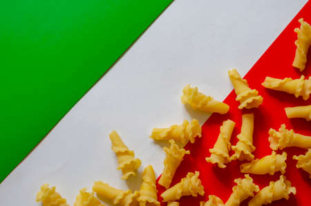 Dry gigli pasta on green-white-red background. Serving of uncooked pasta on tricolor base. Traditional Italian food.の写真素材