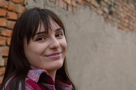 Portrait of cheerful smiling young woman with loose dark hair. Beautiful woman in red plaid shirt...
