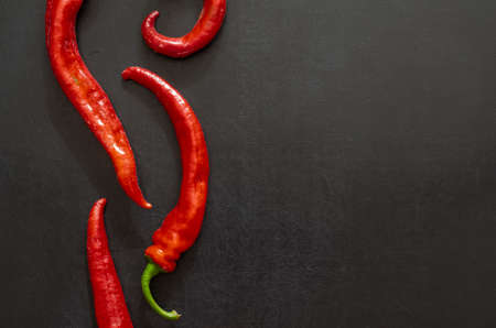 Pods of red hot chili peppers on a black background. Freshly plucked from the farm bed. New crop of hot peppers.の写真素材