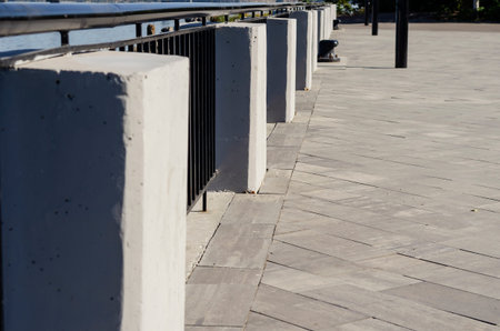 A fragment of the city embankment with concrete pedestals and a metal fence. Black fence along the...