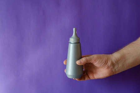 Male hand and gray plastic bottle of syrup. The man is holding a new bottle of sweet syrup for ice cream and desserts. Selective focus.の写真素材