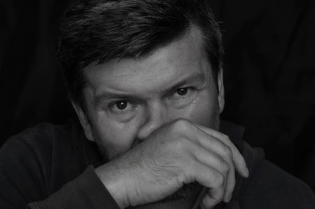 Language of body movements concept. Black and white portrait of an adult man rubbing his own nose...