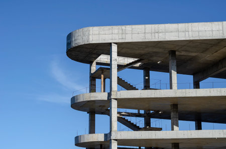 Geometric shape made of concrete on a background of blue sky. Unfinished building of a modern...