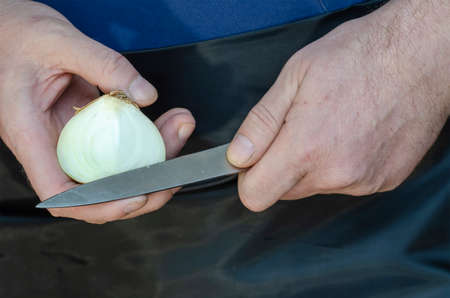 Kitchen knife, ripe onion and men's hands. Hands cut the onion by weight.の写真素材