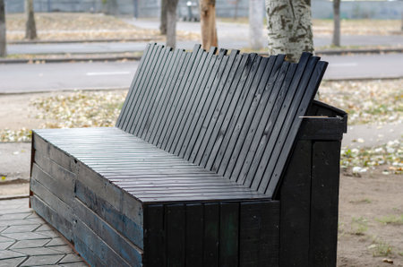 Black wooden street bench against the backdrop of empty city roads. City life. No people.の写真素材