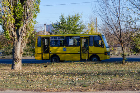 Nikolaev, Ukraine - November 22, 2020: Yellow bus drives down country road with passengers wearing medical masks. Public transport, coronavirus, quarantine.のeditorial素材