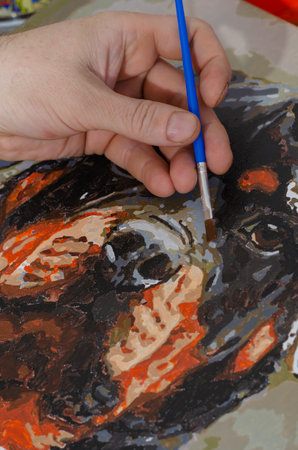Concept of art, creativity and inspiration - man's hand with brush paints picture. Man paints portrait of Rottweiler on canvas. Close-up, selective focus.の写真素材