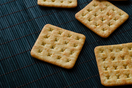 Groceries, snacks, food. Salted crispy crackers on a dark green bamboo napkin.