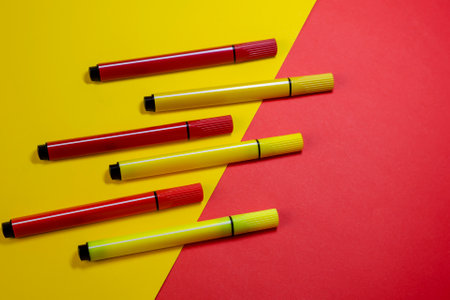Creative two-color composition with red and yellow felt-tip pens. Six colored new felt-tip pens on a red and yellow background.の写真素材